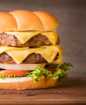 Mouth-watering double cheeseburger with fresh ingredients on a wooden surface, perfect for food lovers.