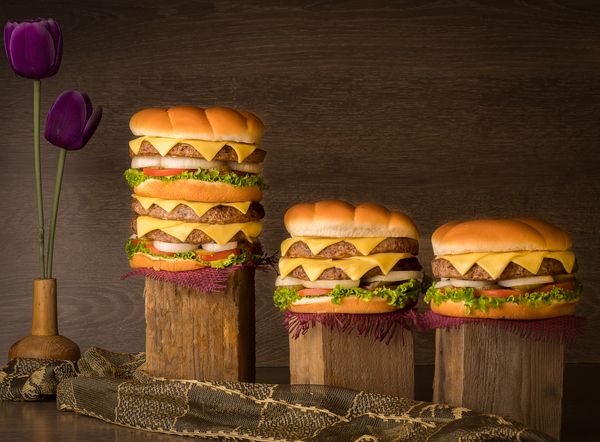 Stacked cheeseburgers on wooden blocks — photo by Mounir Salah on Pexels