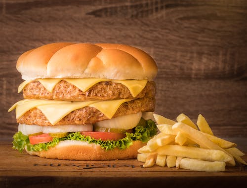 Close-Up Shot of Delicious Cheeseburger and French Fries on Wooden Surface
