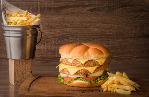 Close-Up Shot of Delicious Cheeseburger and French Fries on Wooden Surface
