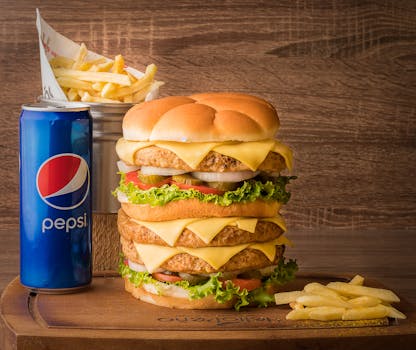 Appetizing triple cheeseburger with fries and Pepsi, perfect for fast food lovers.