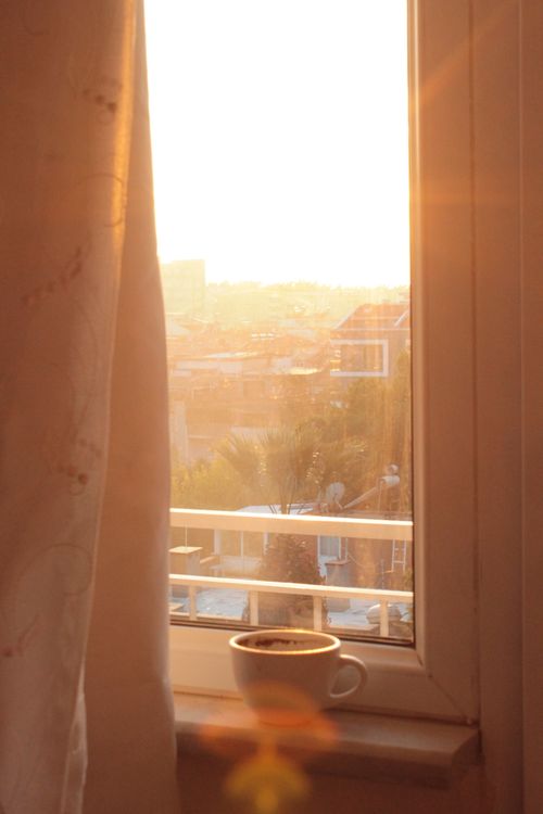 Free Sunlit room with a steaming cup of coffee on the windowsill, creating a calming morning scene. Stock Photo