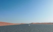 一条废弃的高速公路在晴朗的蓝天下，穿过干旱的沙漠景观延伸而去