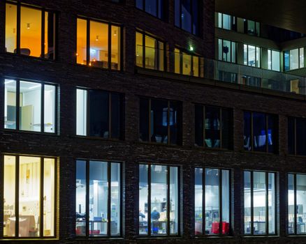 Night view of a modern office building facade with illuminated windows showcasing varied interior lighting.