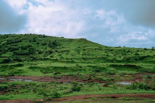 Free Serene landscape of rolling green hills beneath a cloudy sky in Dhom, Maharashtra, India. Stock Photo