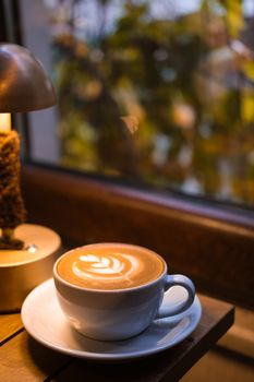 Warm café ambiance with a cup of latte showcasing delicate latte art.