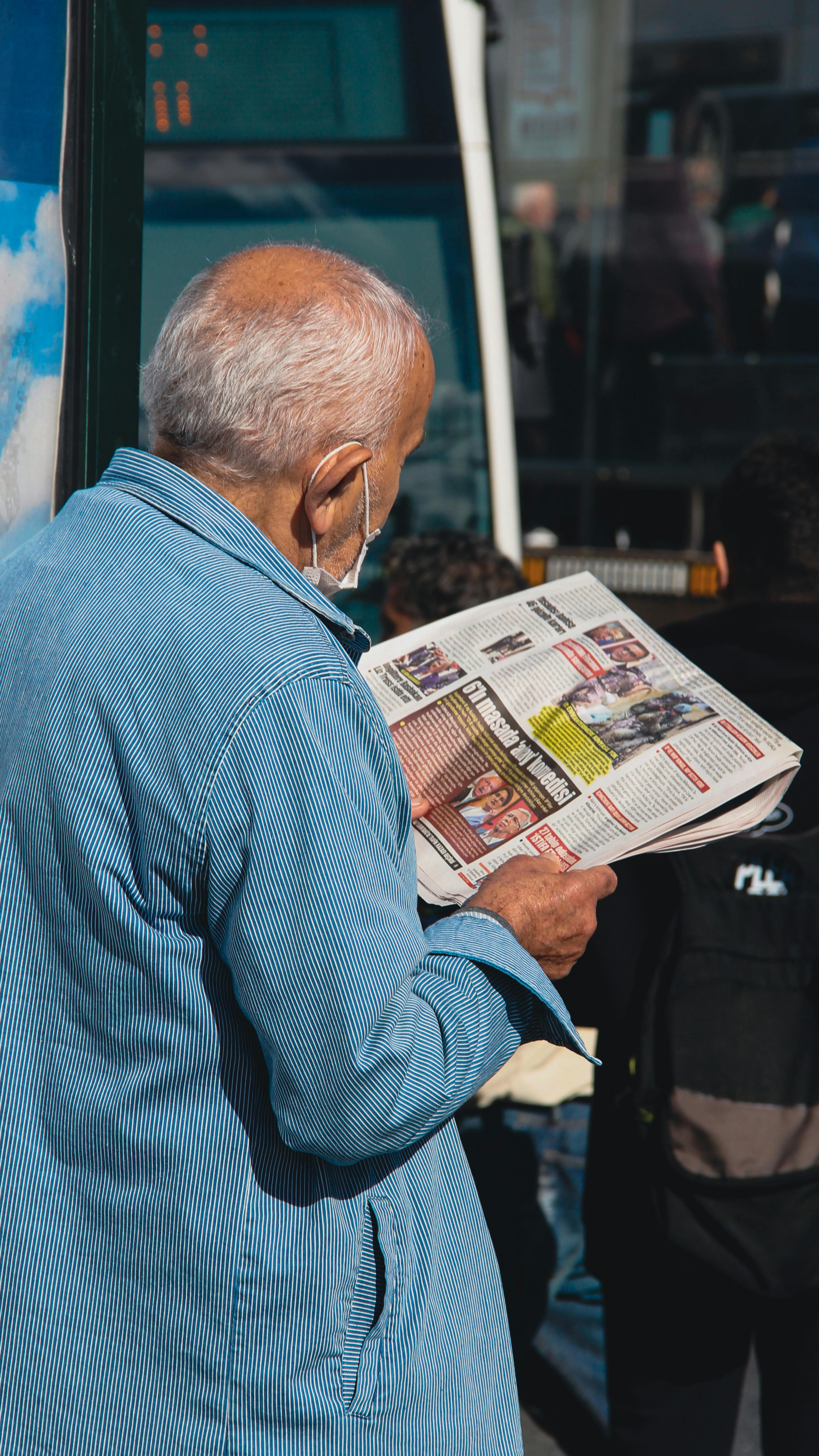 eldery man reading a newspaper in the street