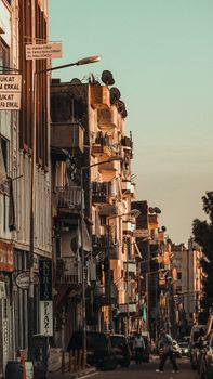 City street with sunlit buildings and parked vehicles in a warm, urban setting.