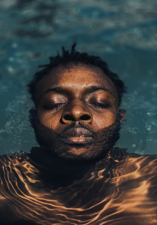Free A serene portrait of a man enjoying a peaceful float in a sunlit swimming pool. Stock Photo