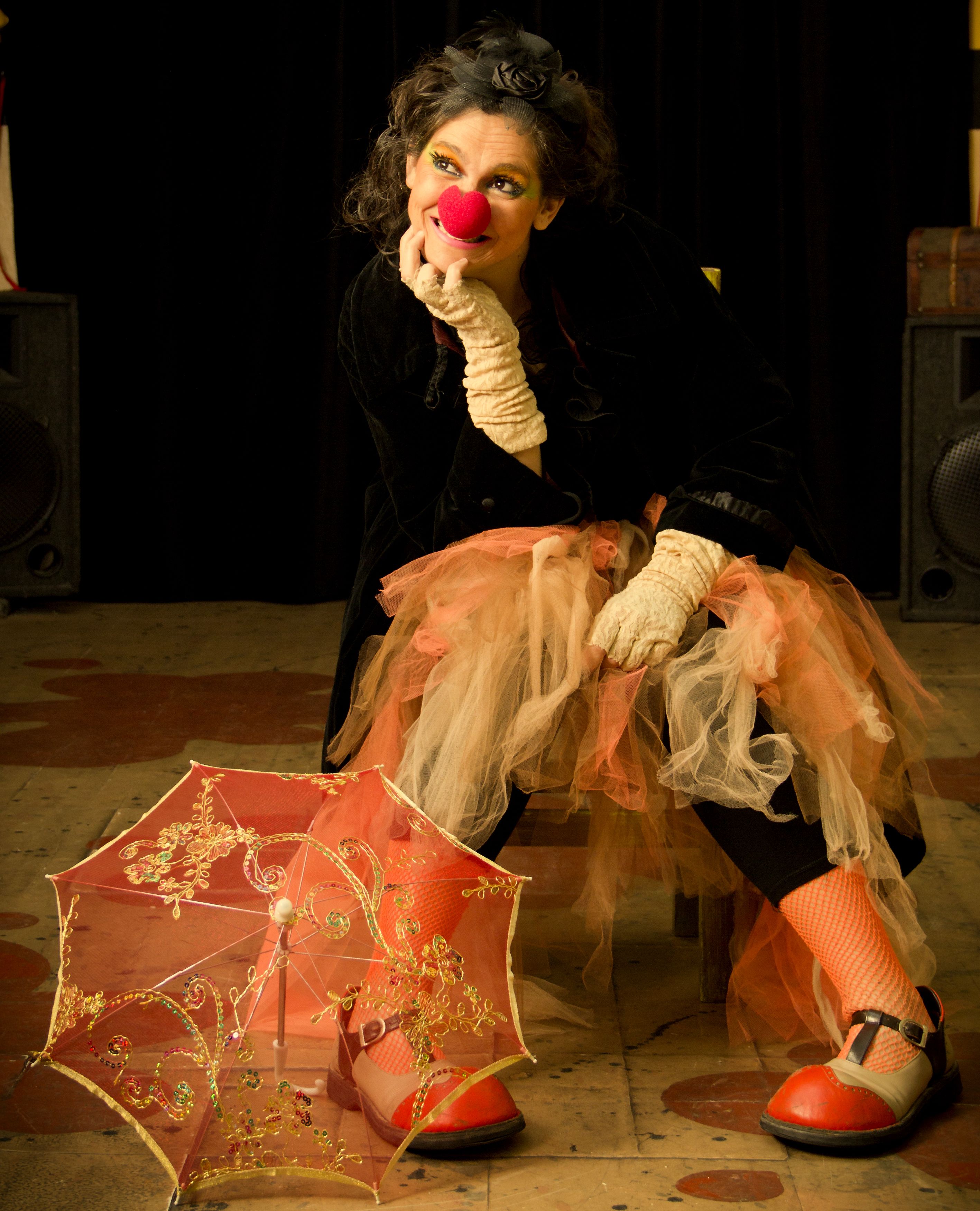 Portrait of a clown in colorful attire with a whimsical expression and red nose.