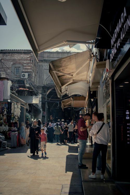 Free Vibrant street scene capturing everyday life in a Middle Eastern marketplace with people walking and shopping. Stock Photo