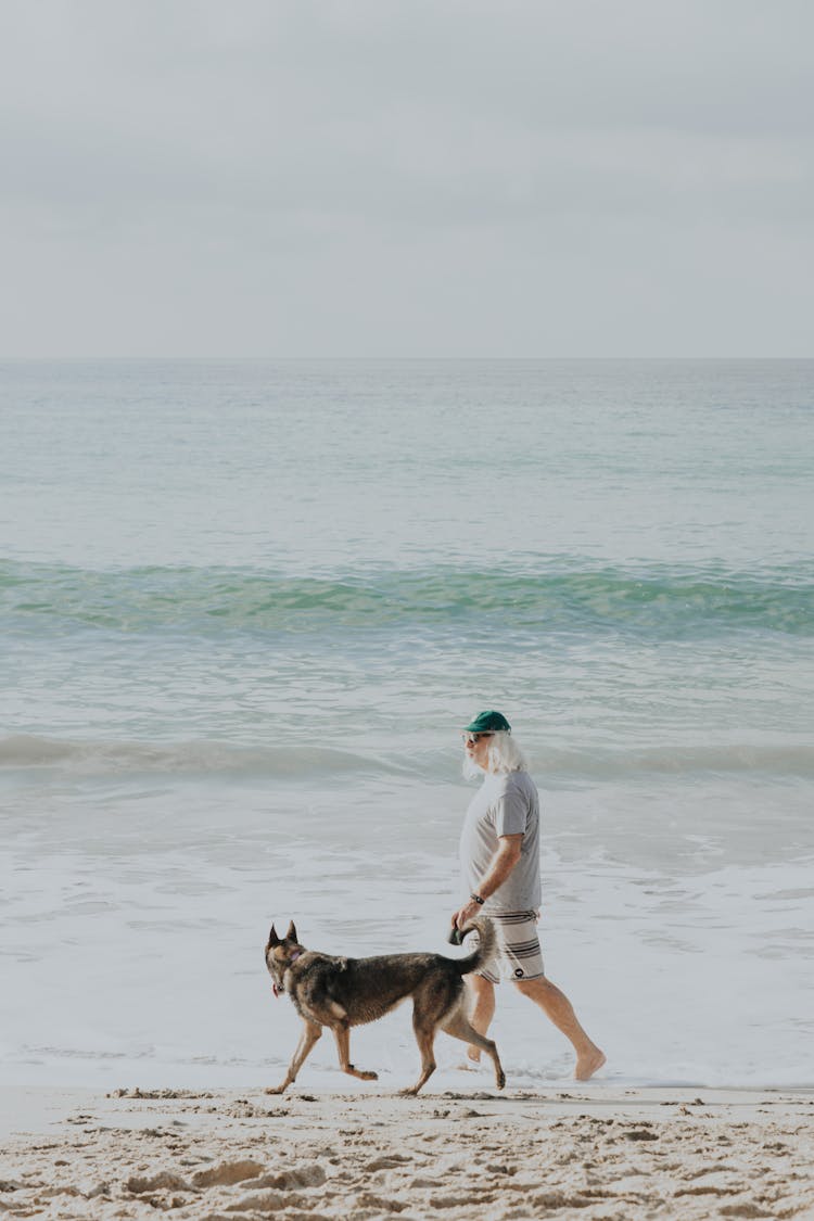 Man Walking On Beach With Dog