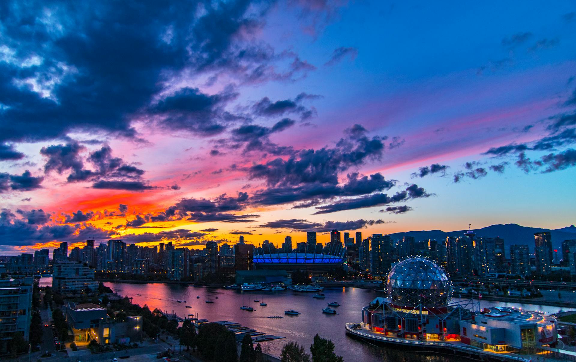 Dramatic sunset over Vancouver skyline featuring Science World and vibrant clouds.