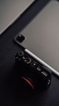 Close-up of a digital camera and tablet on a dark surface, ideal for tech and photography themes.