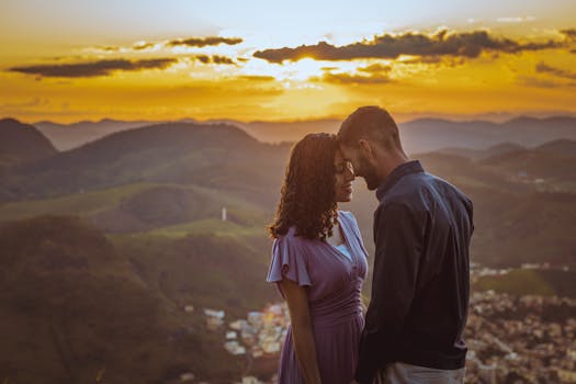 A couple shares a tender moment on a mountainside during a beautiful sunset, symbolizing love and adventure.