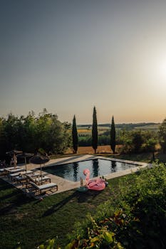 Idyllic France countryside scene with a pool, loungers, and a flamingo float at sunset.