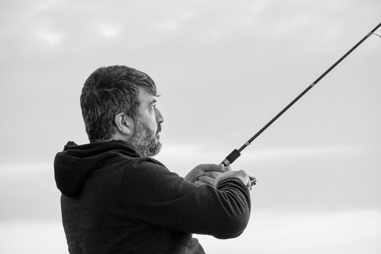 A Man In Black Hoodie Holding A Fishing Rod