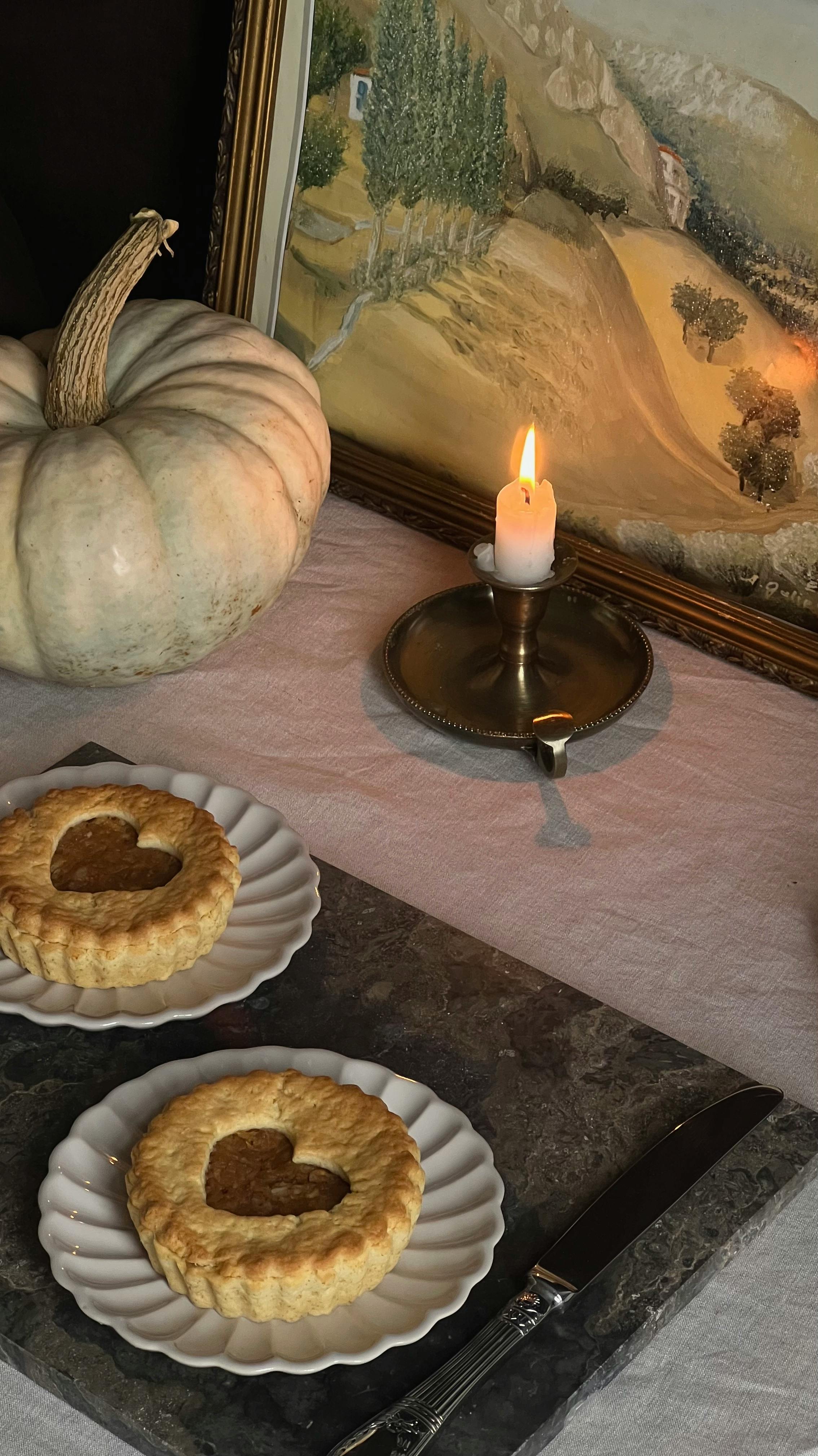 Warm autumn dessert setting with pastries, candle, and pumpkin for a cozy feel.