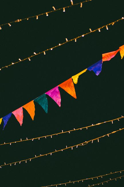 Vibrant flags and string lights against a dark night sky create a festive atmosphere.