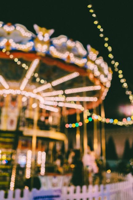 Blurry image of a carousel lit up at night, capturing the festive atmosphere of an amusement park.