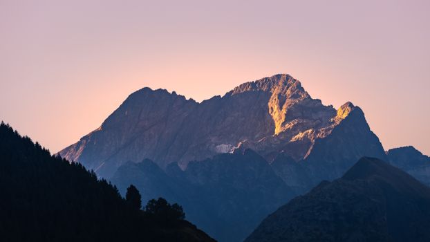 Capture of Alpine peaks at dawn in Écrins with warm sunlight highlighting the mountains.