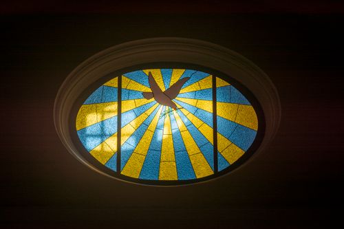 Free Colorful oval stained glass window featuring a dove in Teguise, Spain church. Stock Photo
