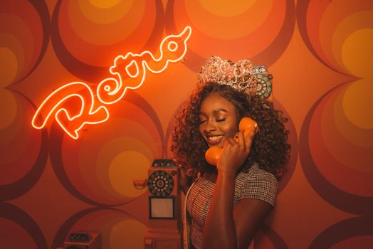 Happy woman with crown using vintage phone in retro studio.