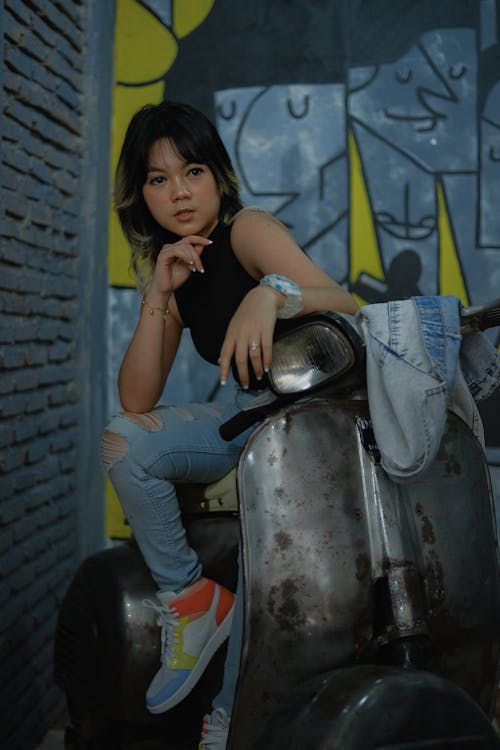 Woman in Black Tank Top Sitting on Motor Scooter 