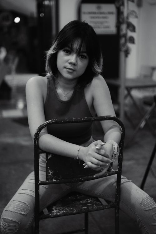 Free Grayscale image capturing a woman sitting confidently on a chair in an urban setting. Stock Photo