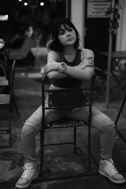 Free Grayscale photo of a woman sitting confidently in a chair with arms crossed. Stock Photo
