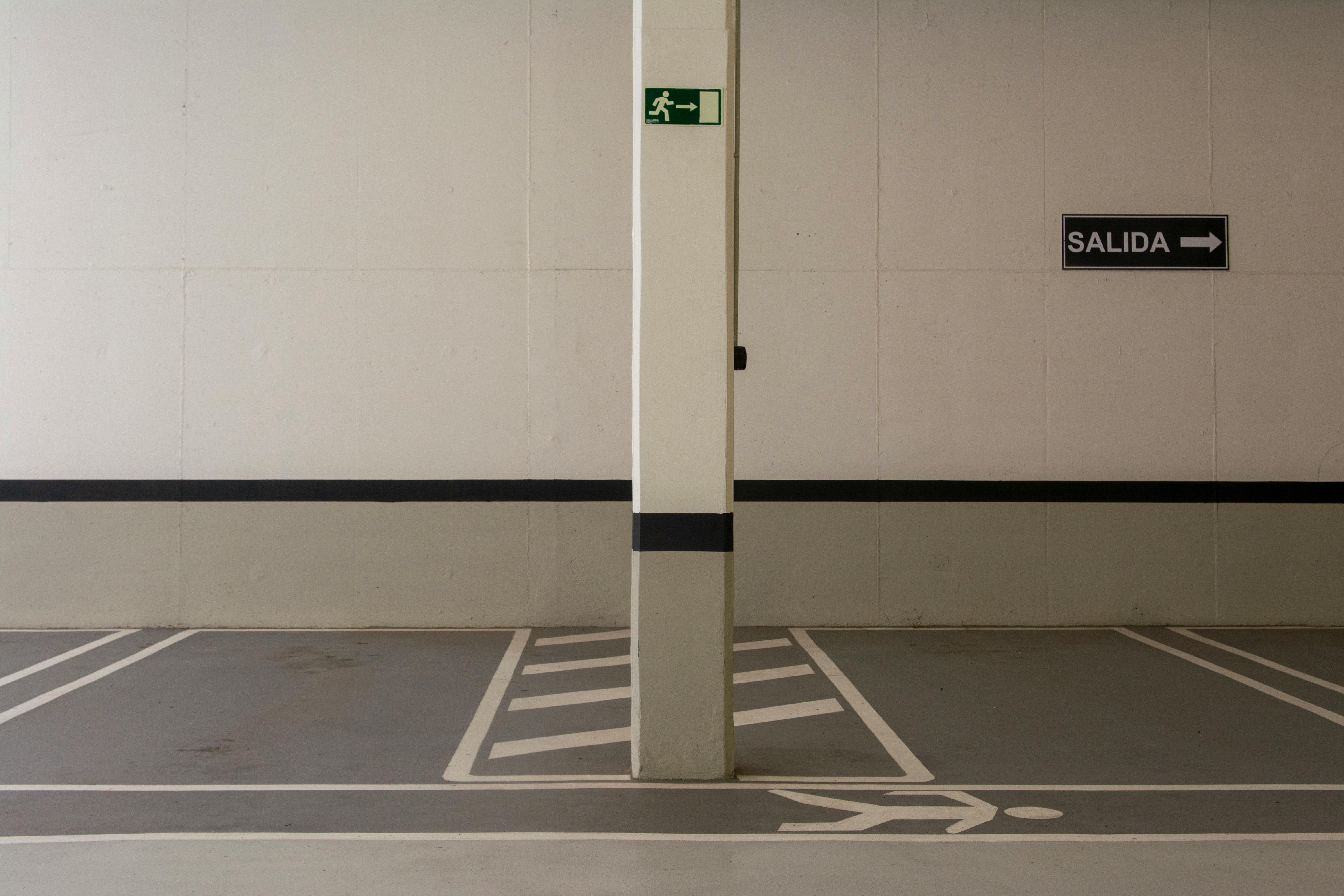 Minimalist underground parking area with exit signs and marked pathways.