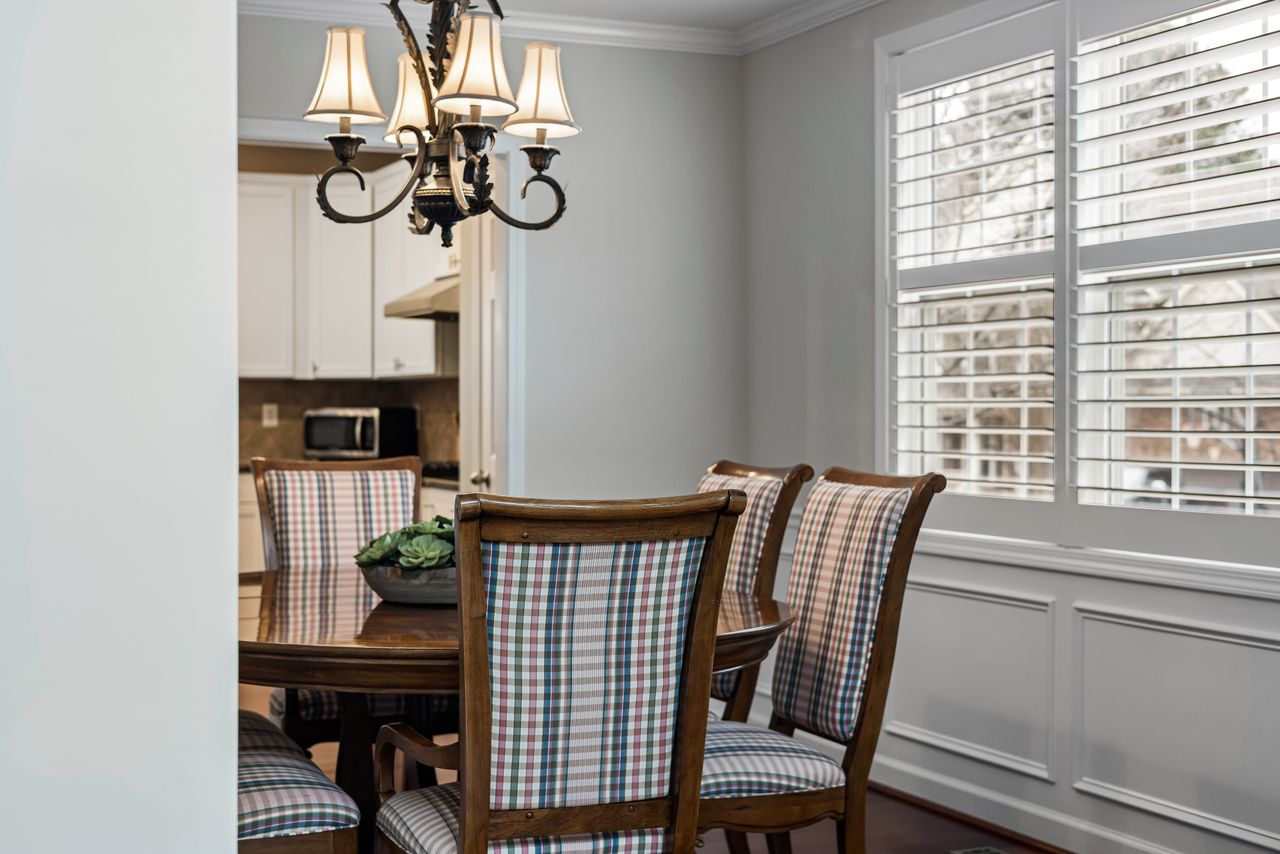 Round dark wood table with plaid upholstered dining chairs