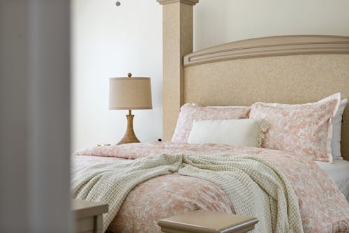 A Cozy Bed with Pillows and Knitted Blanket Near the Lampshade