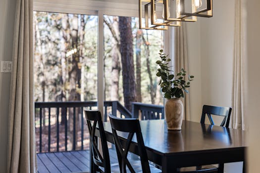 A stylish dining room featuring a contemporary table setup with a flower vase and soft lighting.