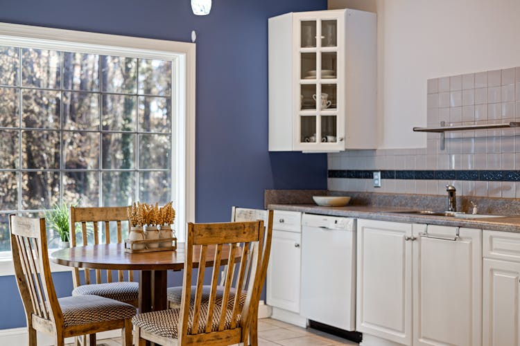 A Wooden Table And Chairs Near The Kitchen Cabinets