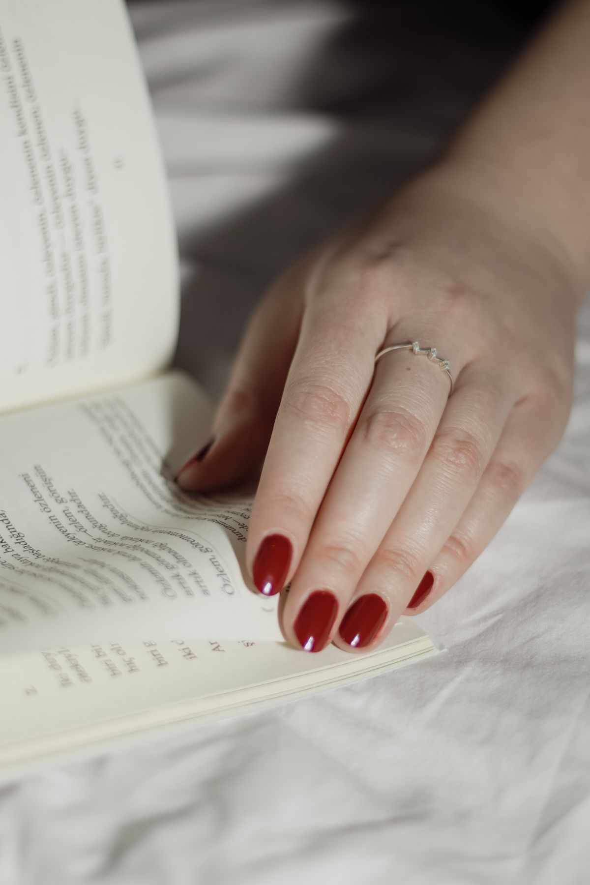 Close-up of a red-manicured hand turning a book page. Elegant simplicity.