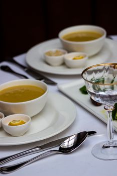 A refined table setting featuring delicious soup, wine glass, and elegant crockery in a restaurant setting.