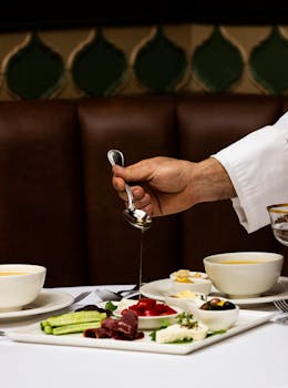 Chef serving a gourmet dish with fresh ingredients at a stylish restaurant table.