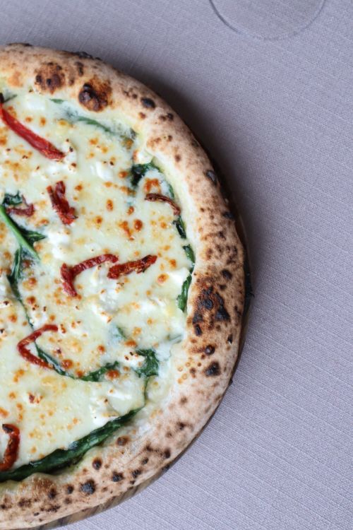 Free Mouthwatering cheese pizza with spinach and sun-dried tomatoes, top view. Stock Photo