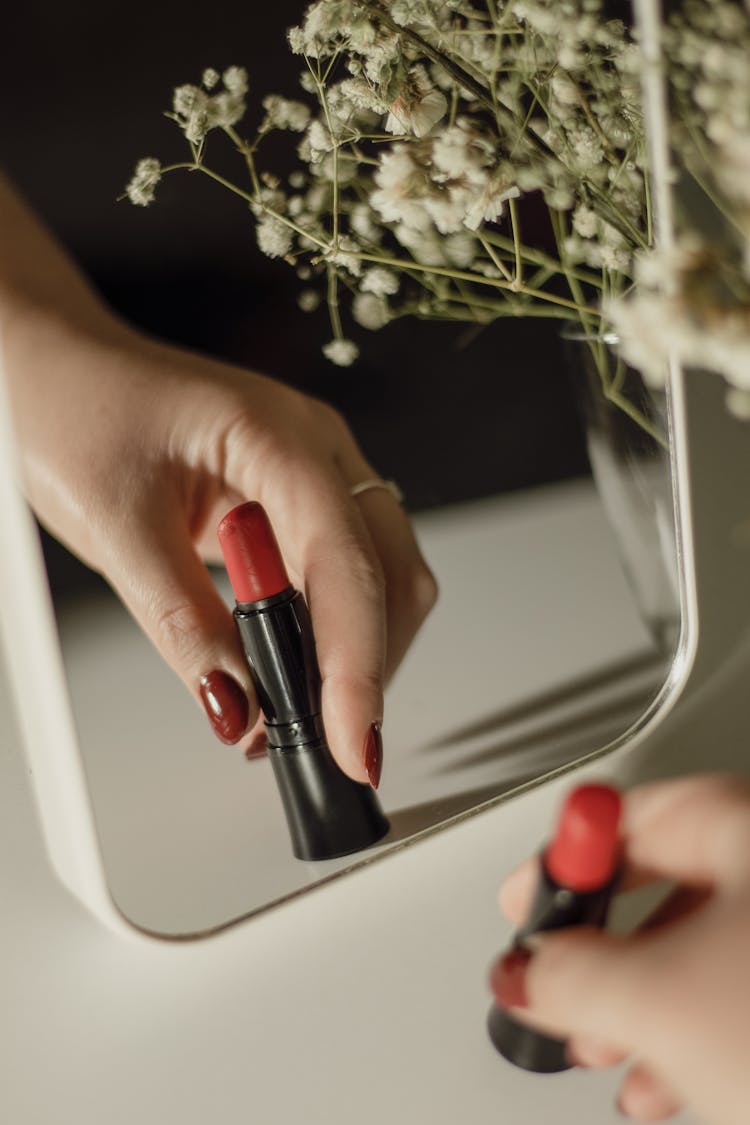 Woman Hand With Lipstic Reflected In Mirror