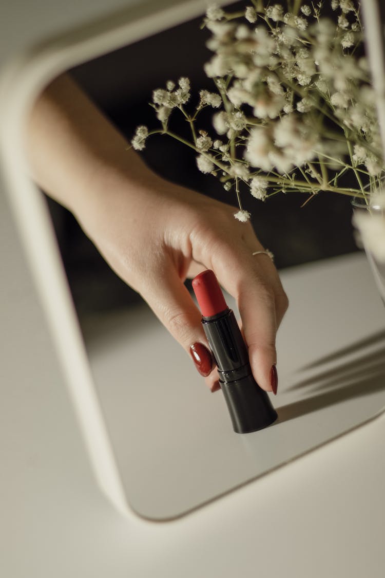 Woman Hand With Lipstic Reflected In Mirror