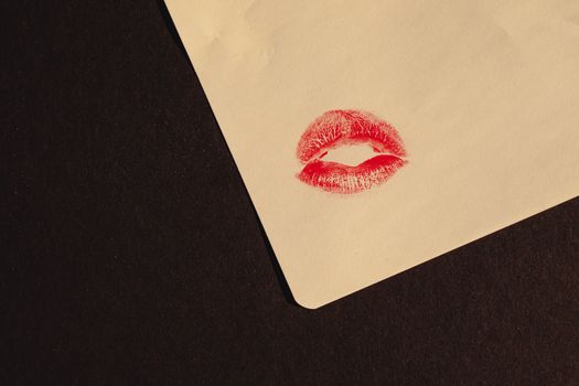 Close-up of a red lipstick kiss imprint on paper with copy space, symbolizing romance and affection.
