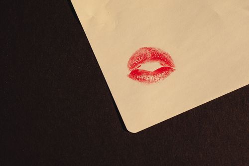 Free Close-up of a red lipstick kiss imprint on paper with copy space, symbolizing romance and affection. Stock Photo