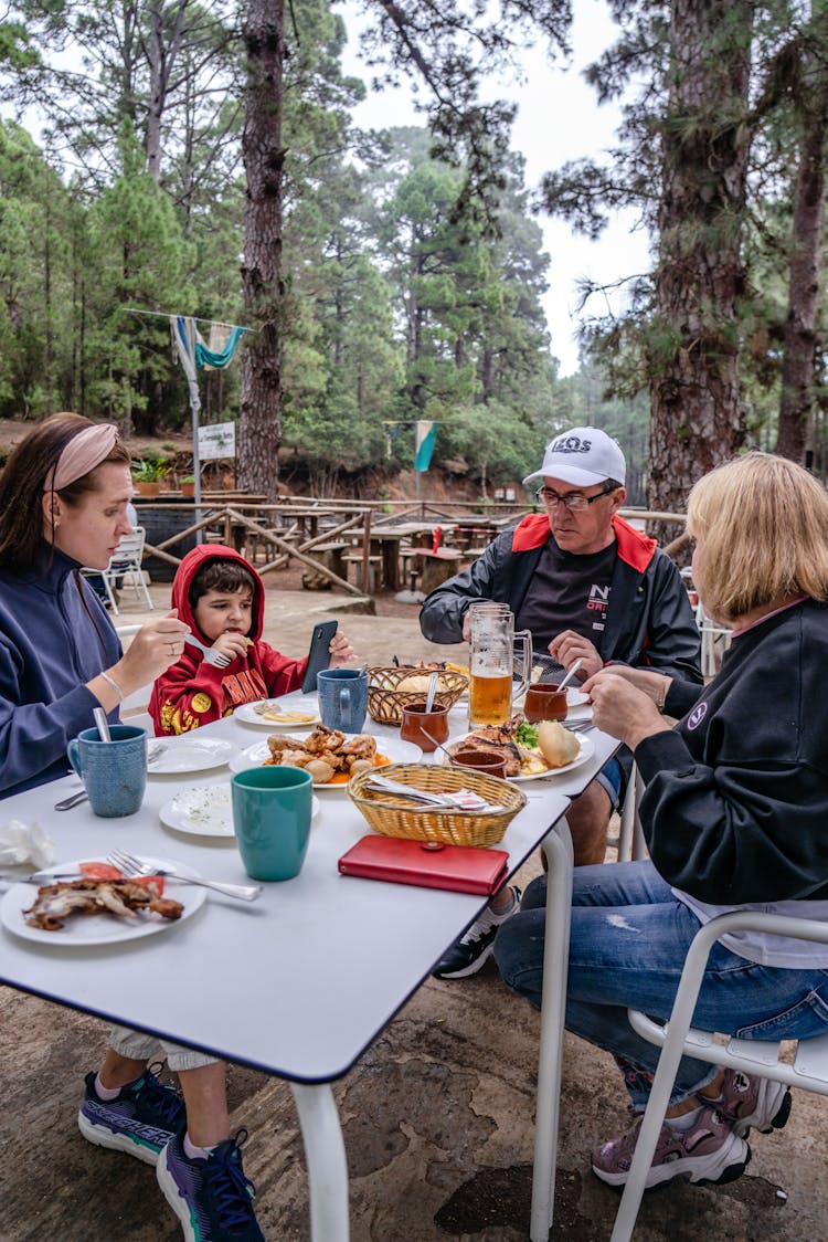 Family Eating At Picnic Table In Forest