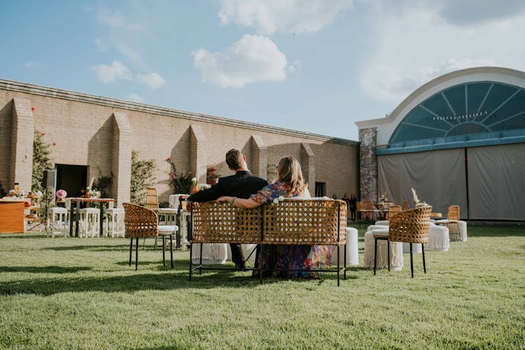 Back View Of A Couple Sitting On A Bench In A Restaurant Patio