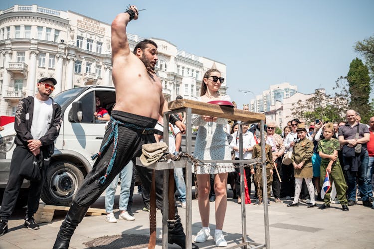 Athlete Demonstrating His Strength On A City Street, And Crowd Watching