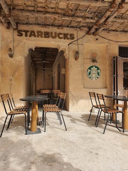 A rustic-themed Starbucks café featuring outdoor seating and a thatched roof entrance.