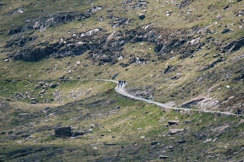 People Hiking on Trail through Mountainside