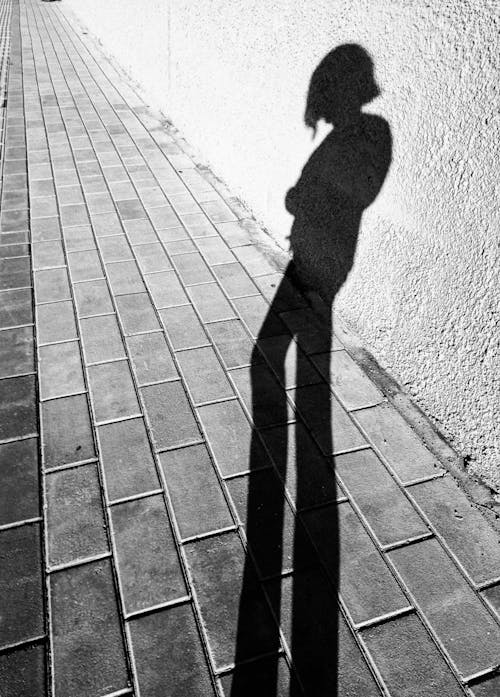 A Shadow of a Person Standing on Brick Floor