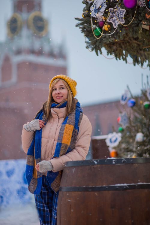 Free Caucasian woman in winter attire enjoying a festive day outdoors with decorated Christmas tree. Stock Photo